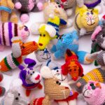 Colorful, crocheted animal toys in various shapes and patterns are arranged on a white surface.