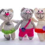 Three crocheted cat dolls standing in a row against a white background.